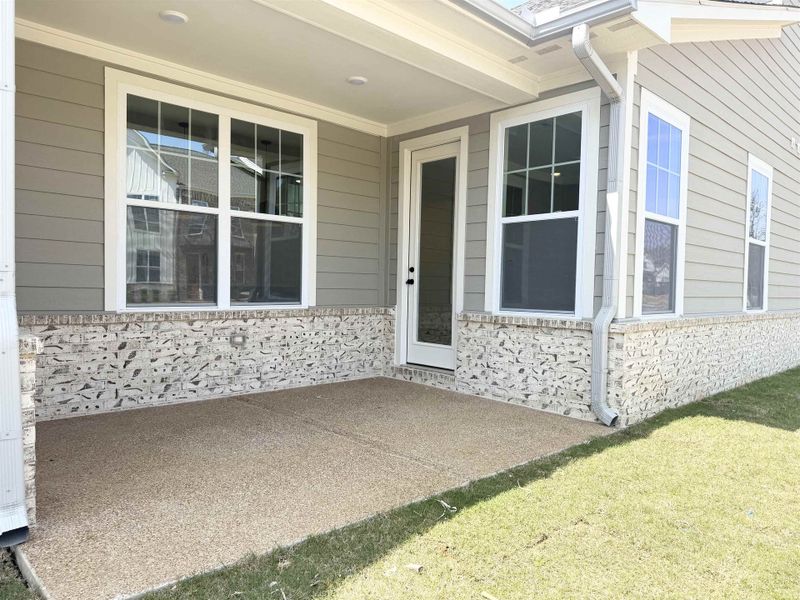 Doorway to property with a patio, a yard, and stone siding