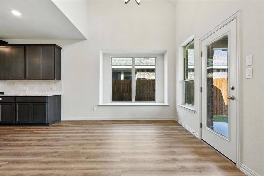 Unfurnished living room with light wood finished floors and a towering ceiling