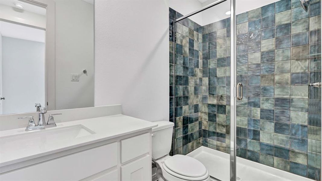 Bathroom featuring a shower with shower door, vanity, and toilet