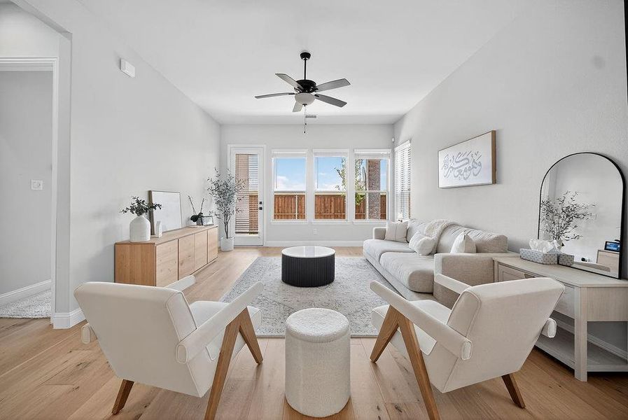 Spacious living area featuring high ceilings, wood-finish flooring, and ample natural light from multiple windows
