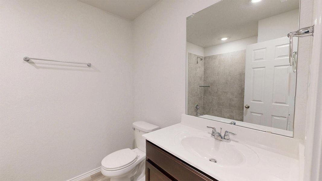 A well-appointed bathroom features a single vanity, a standard toilet, and a tiled shower with a glass shelf.