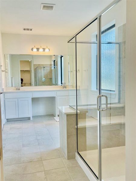 Bathroom featuring a walk in closet, light tile patterned floors, a shower stall, and vanity Bathroom featuring a walk in closet, light tile patterned floors, a shower stall, and vanity
