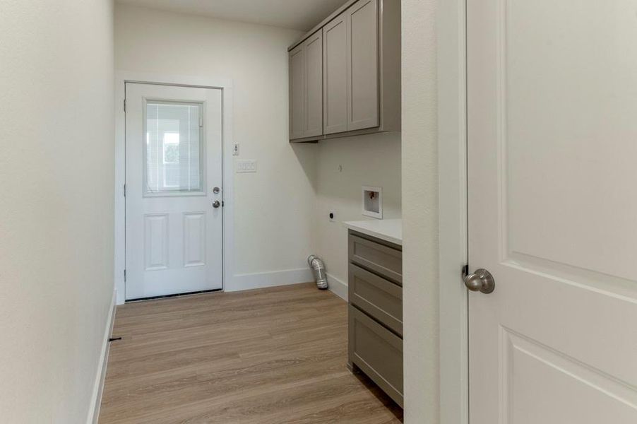 Washroom featuring light wood finished floors, cabinet space, and hookup for an electric dryer
