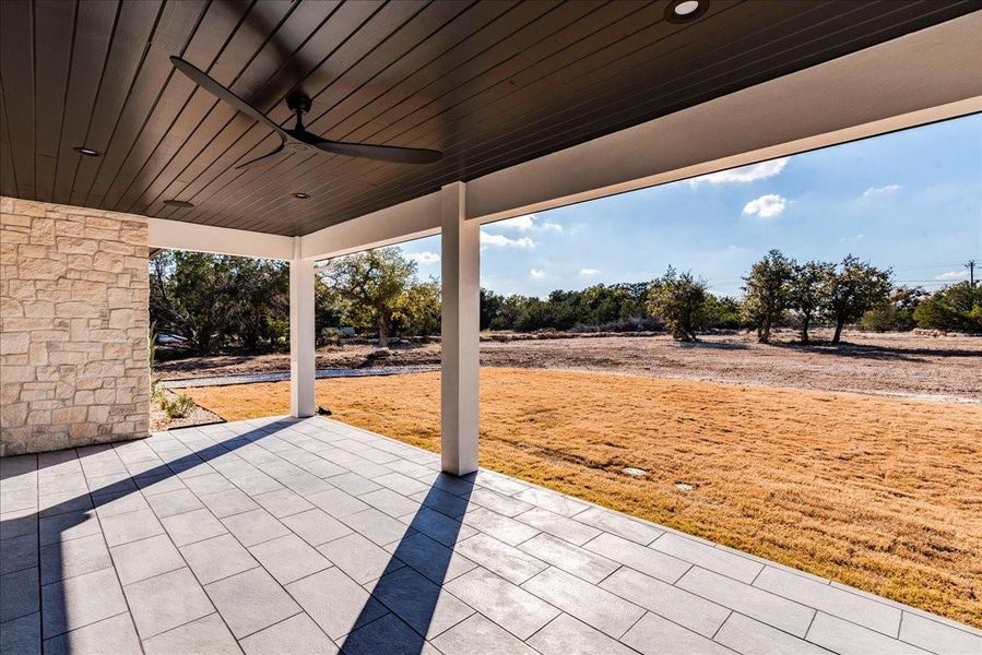 The outdoor covered patio boasts a tongue-and-groove ceiling, a custom ceiling fan, and tiled flooring, creating a perfect space for relaxation and outdoor entertaining.