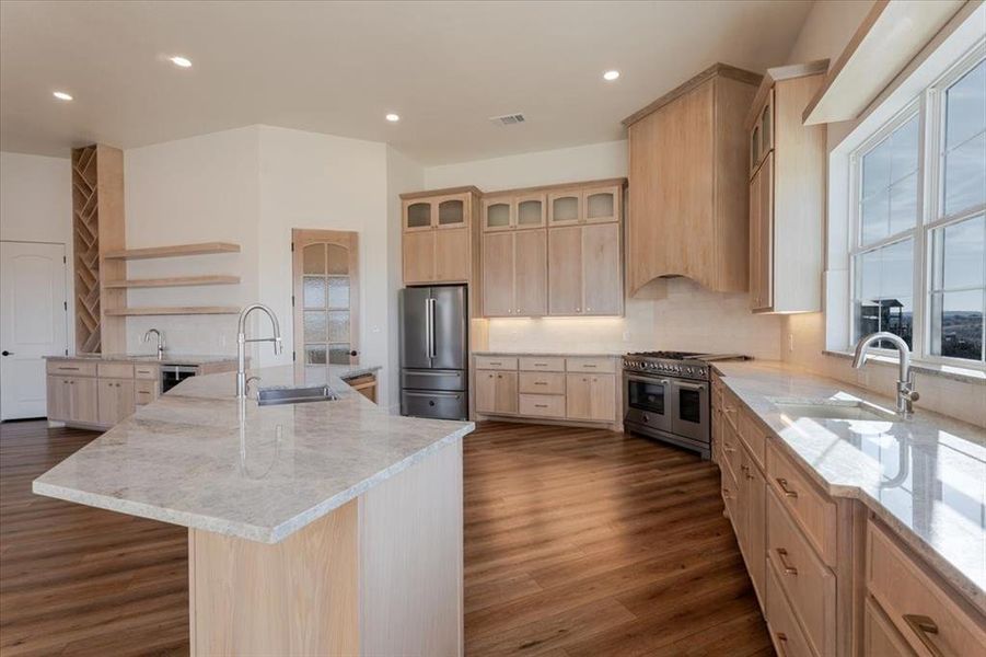 Kitchen featuring light brown cabinetry, stainless steel appliances, open shelves, and a sink Kitchen featuring light brown cabinetry, stainless steel appliances, open shelves, and a sink