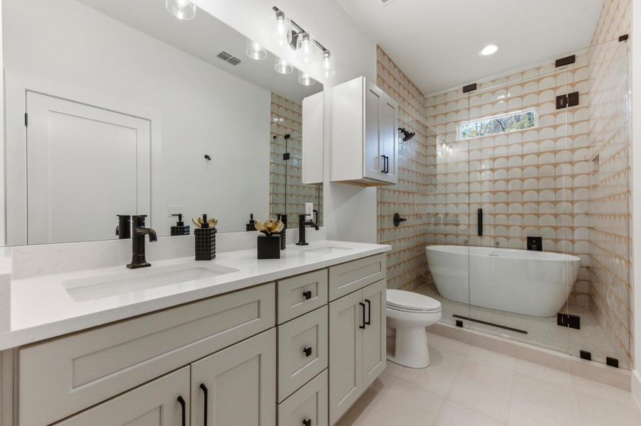 Bathroom featuring double vanity, a freestanding tub, light tile patterned floors, and a stall shower