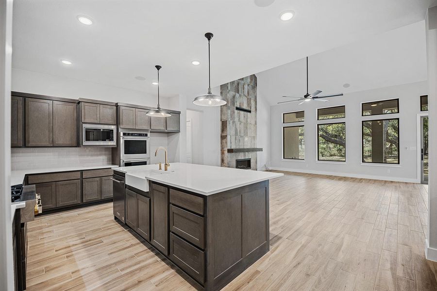Kitchen with a sink, decorative backsplash, ceiling fan, dark brown cabinets, and appliances with stainless steel finishes Kitchen with a sink, decorative backsplash, ceiling fan, dark brown cabinets, and appliances with stainless steel finishes