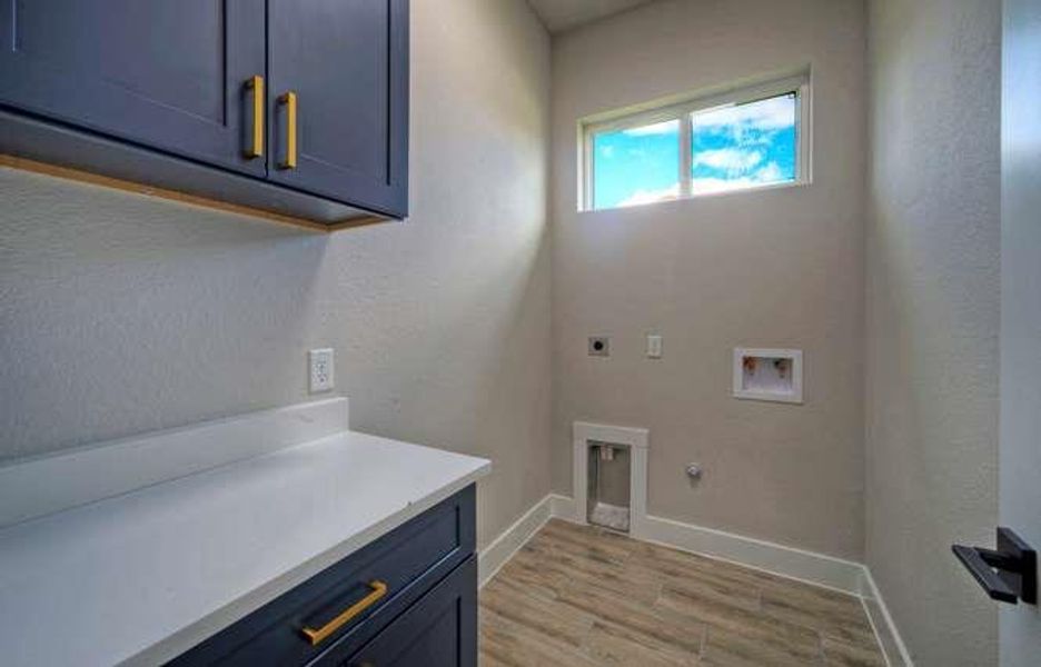 Functional laundry room offers a convenient counter space with overhead and base cabinetry, alongside durable flooring.