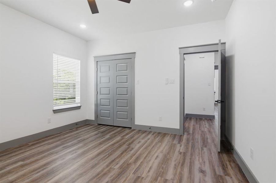 Spacious room featuring wood-finish flooring, white walls, and recessed lighting