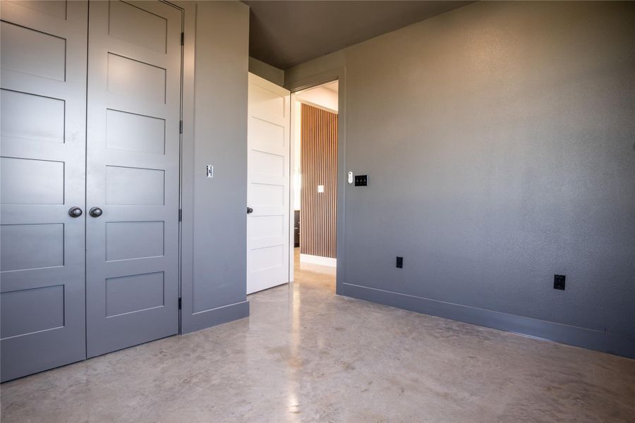 Unfurnished bedroom with finished concrete flooring and a closet