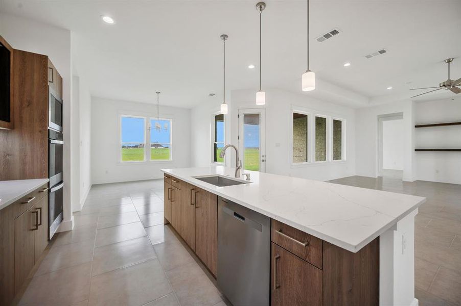 Kitchen with a sink, modern cabinets, a spacious island, a ceiling fan, and appliances with stainless steel finishes Kitchen with a sink, modern cabinets, a spacious island, a ceiling fan, and appliances with stainless steel finishes