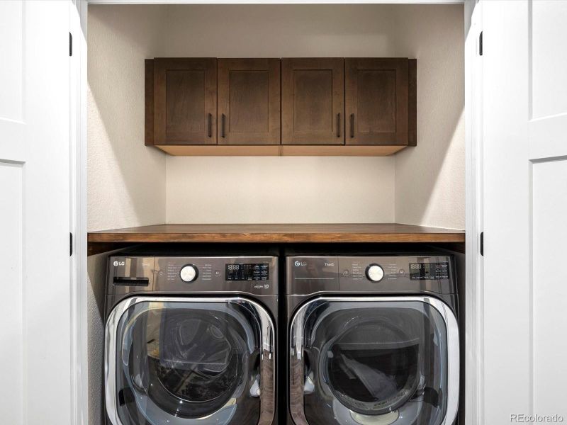 Laundry with custom folding shelf above and cabinets for storage. Laundry with custom folding shelf above and cabinets for storage.