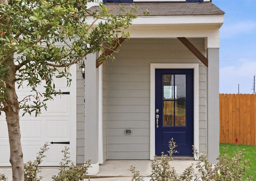 Covered front porch and entry featuring a navy front door with side lite window and landscaped beds.