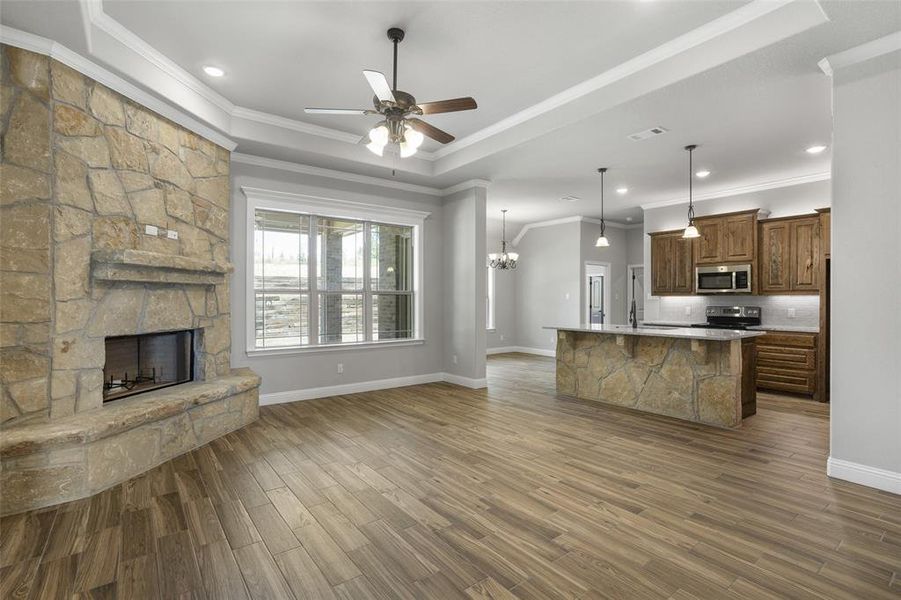 Unfurnished living room featuring a fireplace, hardwood / wood-style floors, a raised ceiling, and ornamental molding