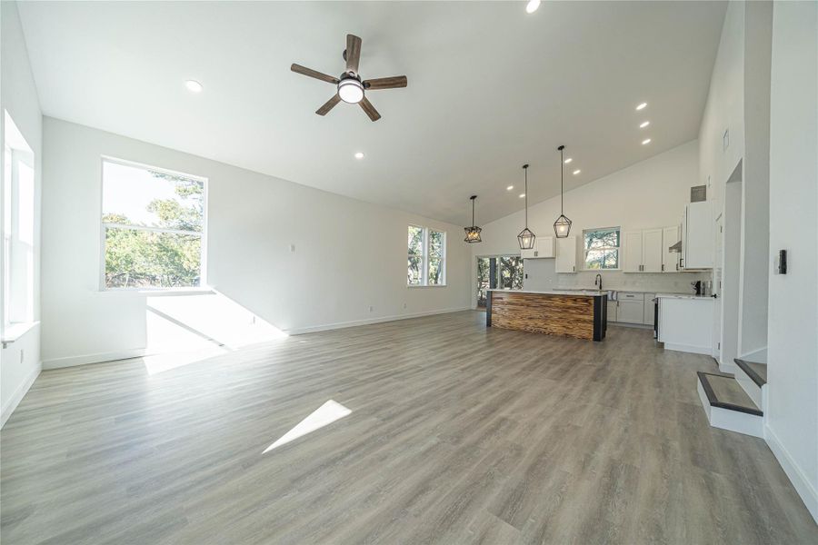 Unfurnished living room with a ceiling fan, light wood-type flooring, recessed lighting, and high vaulted ceiling