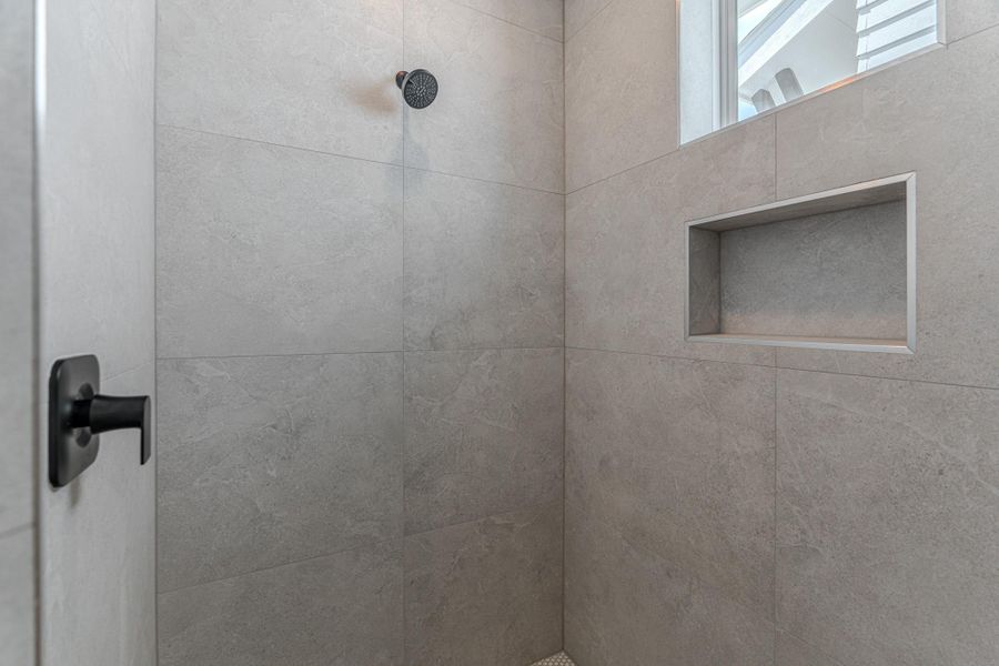 This is a modern shower with sleek gray tiles, a built-in niche for storage, and a large window for natural light. The matte black fixtures add a contemporary touch.Photo Disclaimer: Photos are representative of the community and may depict a similar floor plan, model home, or previously completed residence. This is a modern shower with sleek gray tiles, a built-in niche for storage, and a large window for natural light. The matte black fixtures add a contemporary touch.Photo Disclaimer: Photos are representative of the community and may depict a similar floor plan, model home, or previously completed residence.