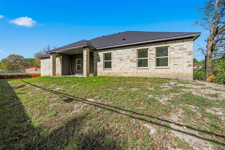 Rear view of house with a patio, brick siding, and roof with shingles Rear view of house with a patio, brick siding, and roof with shingles