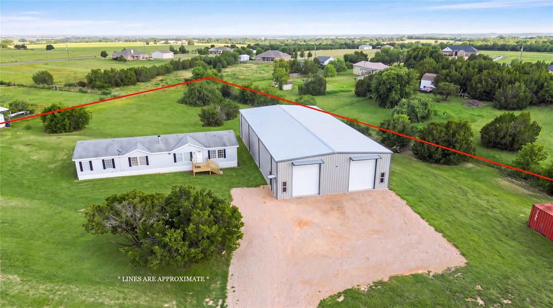 An expansive rural property features a residential structure alongside a massive metal workshop building.
