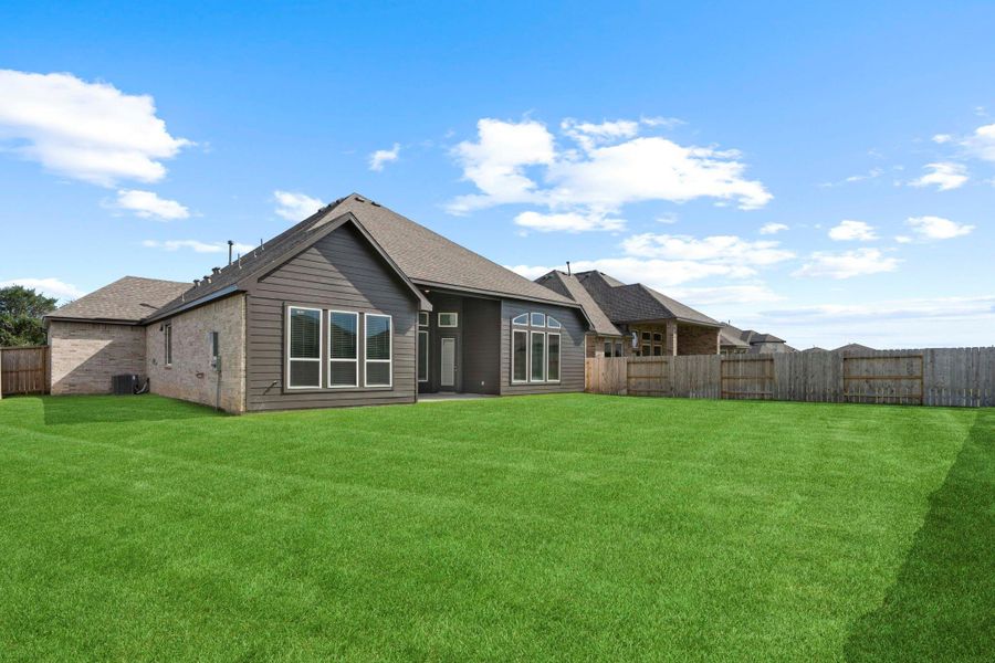 Rear view of the home highlighting the covered patio and expansive backyard, offering plenty of space for outdoor fun.