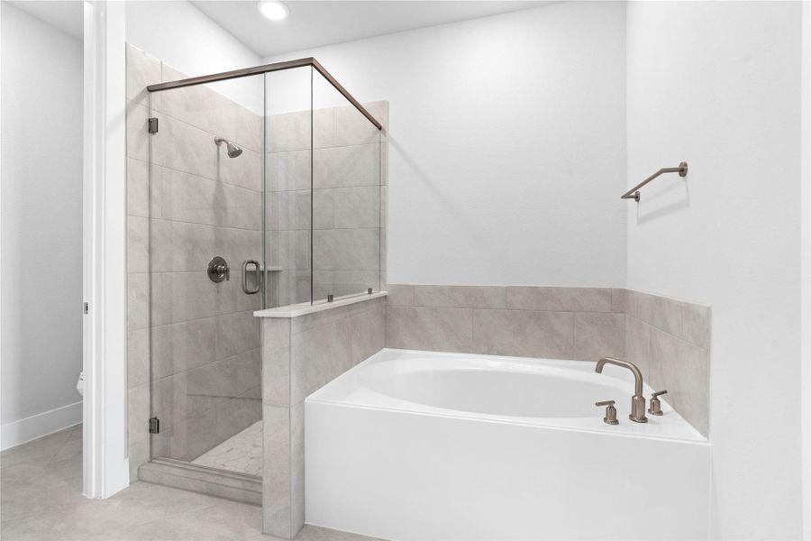 Indulge in relaxation within this spa-inspired primary bathroom, offering both a quick shower and a tranquil soaking experience. The walk-in shower is glass enclosed with modern tile walls and brushed nickel finishes. Indulge in relaxation within this spa-inspired primary bathroom, offering both a quick shower and a tranquil soaking experience. The walk-in shower is glass enclosed with modern tile walls and brushed nickel finishes.