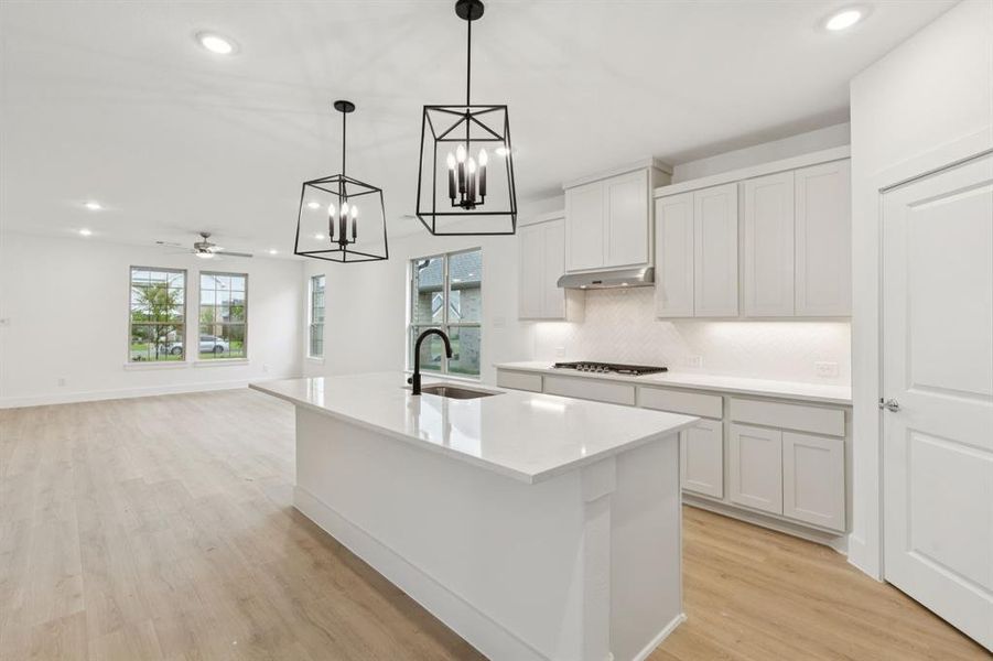Kitchen featuring a chandelier, decorative backsplash, recessed lighting, light wood finished floors, and light countertops Kitchen featuring a chandelier, decorative backsplash, recessed lighting, light wood finished floors, and light countertops