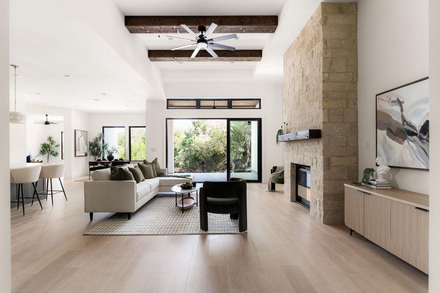 An airy great room showcasing a stone fireplace and elegant hardwood flooring.