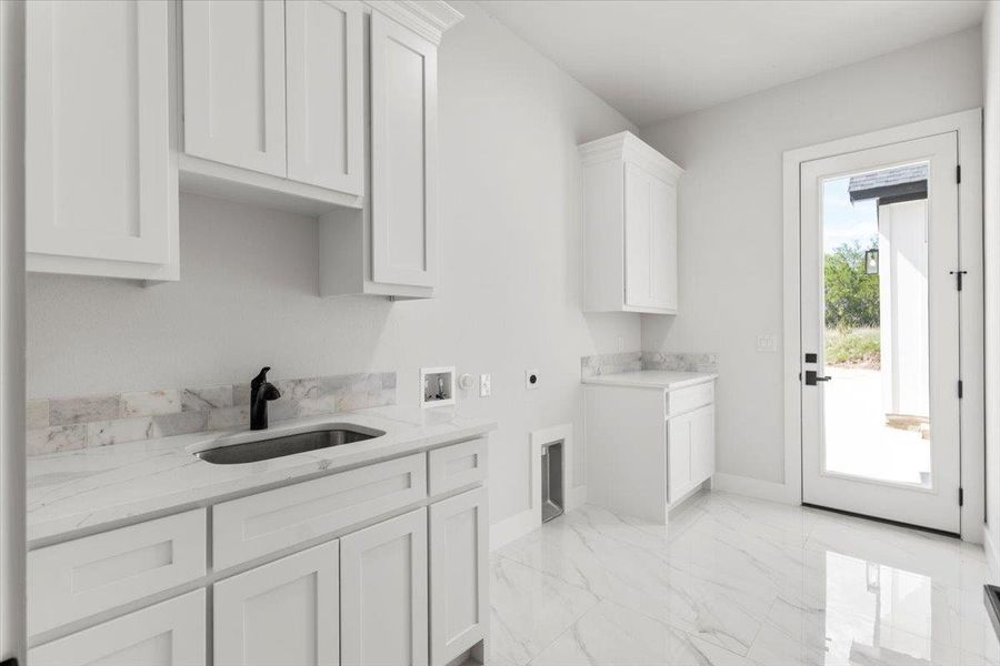 Laundry room with cabinet space, sink, washer hookup, hookup for an electric dryer, light marble finish floors, and baseboards Laundry room with cabinet space, sink, washer hookup, hookup for an electric dryer, light marble finish floors, and baseboards