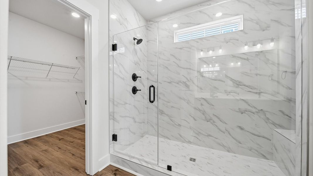 Highly functional and elegant en-suite with refined finishes, tiled walk-in shower, and hardwood floors at Iris Meadows