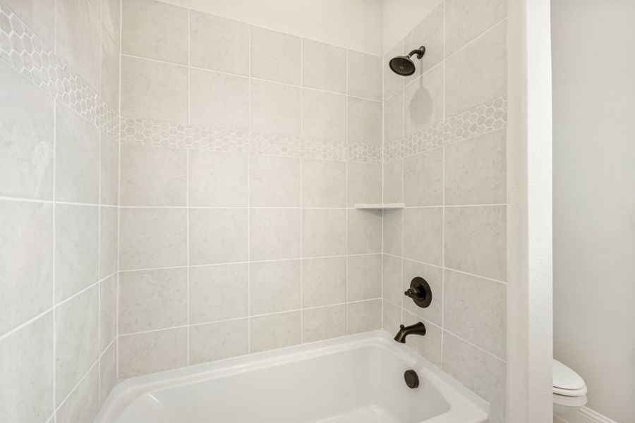 Bathtub and shower combo with white tile surround, hexagon accent border, and oil-rubbed bronze fixtures Bathtub and shower combo with white tile surround, hexagon accent border, and oil-rubbed bronze fixtures