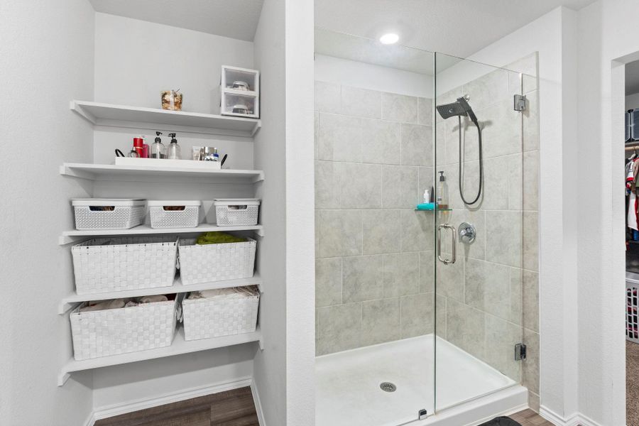 A well-organized closet with ample shelving pairs perfectly with a sleek glass-enclosed shower. A well-organized closet with ample shelving pairs perfectly with a sleek glass-enclosed shower.