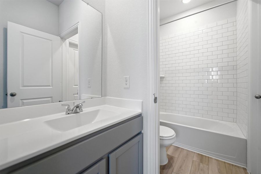 Full bath with double vanity, a shower stall, and a walk-in closet