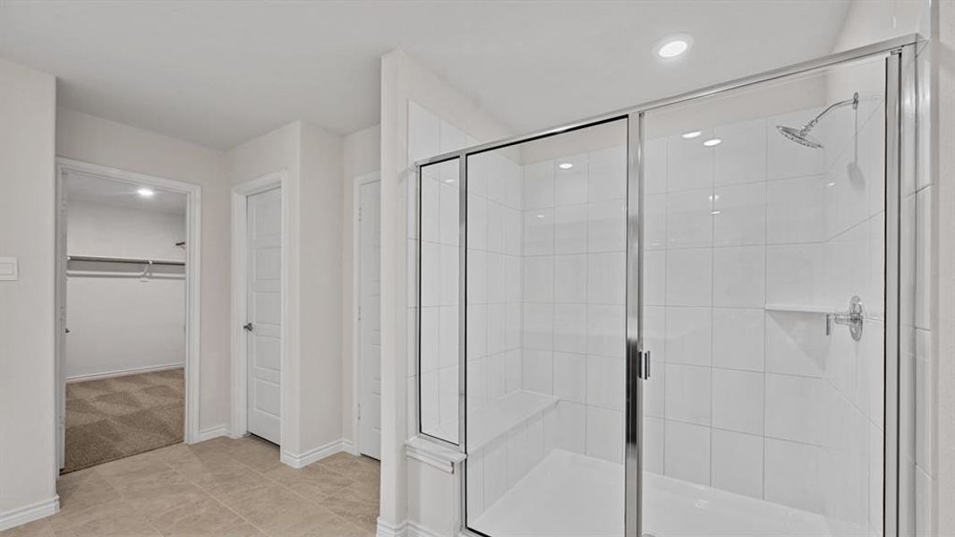 Glass-enclosed shower with a built-in bench, white tile surround, and rainfall showerhead Glass-enclosed shower with a built-in bench, white tile surround, and rainfall showerhead