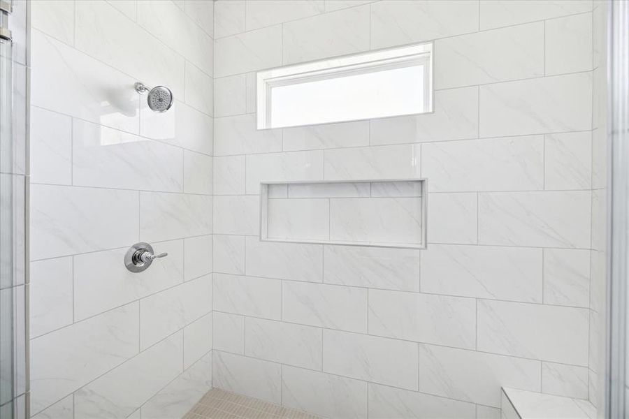 Thoughtfully Designed – This expansive primary shower, a comfortable seating bench, anchored by a mosaic floor, floor to ceiling tiled surround, storage niche, all elegantly enclosed in frameless glass.