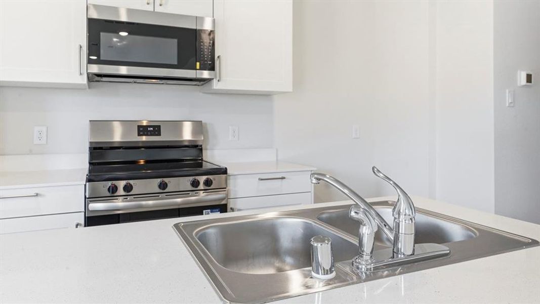 Kitchen featuring stainless steel appliances and white cabinets