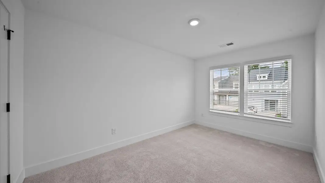 Elegant carpeted bedroom with walk-in closet and wall-to-wall windows offering natural brightness