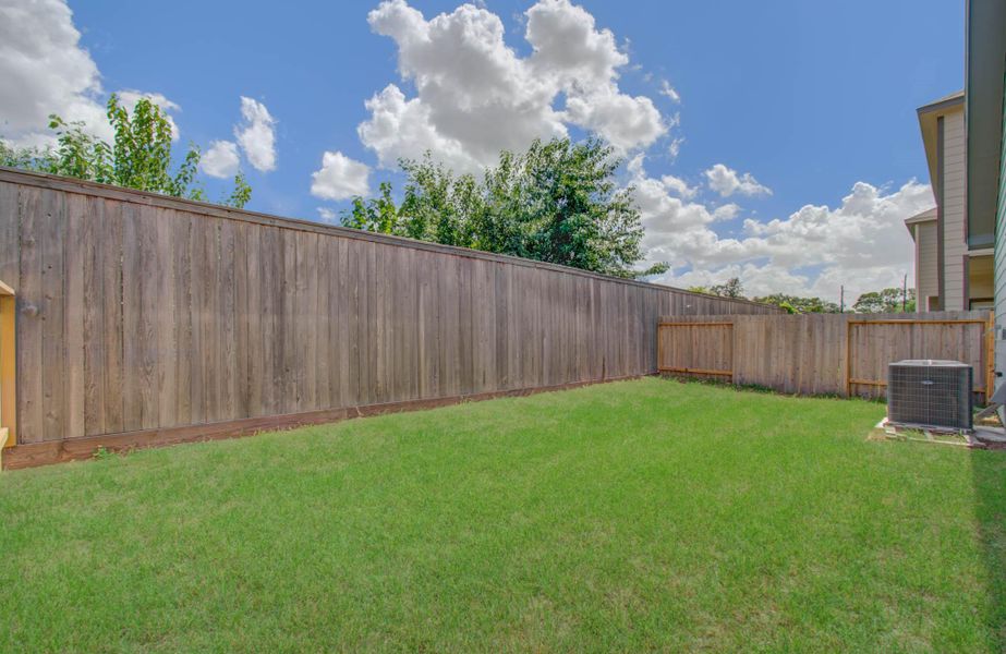Spacious fenced backyard with lush green grass, perfect for outdoor activities and relaxation.