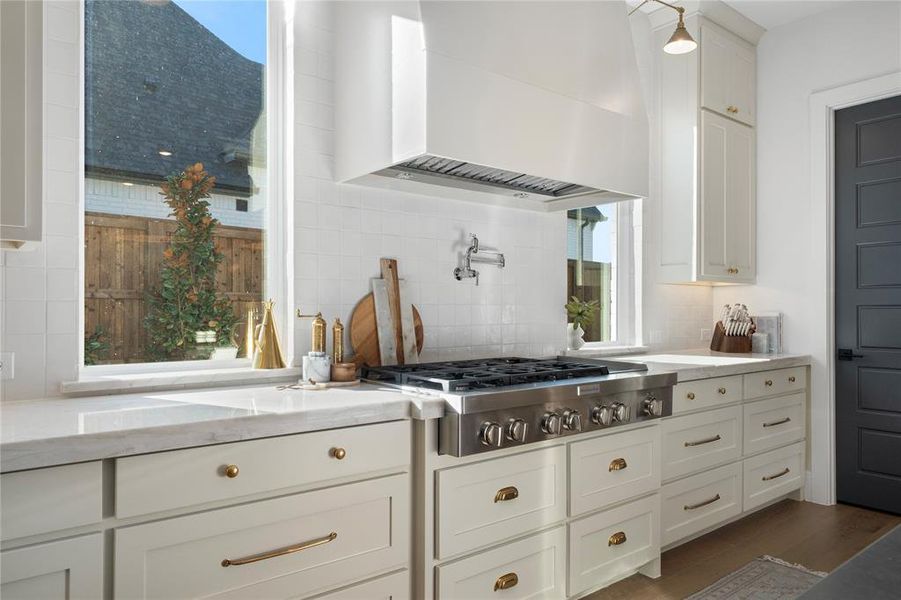 Kitchen with stainless steel gas stovetop, wall chimney range hood, light stone countertops, dark hardwood / wood-style flooring, and white cabinetry