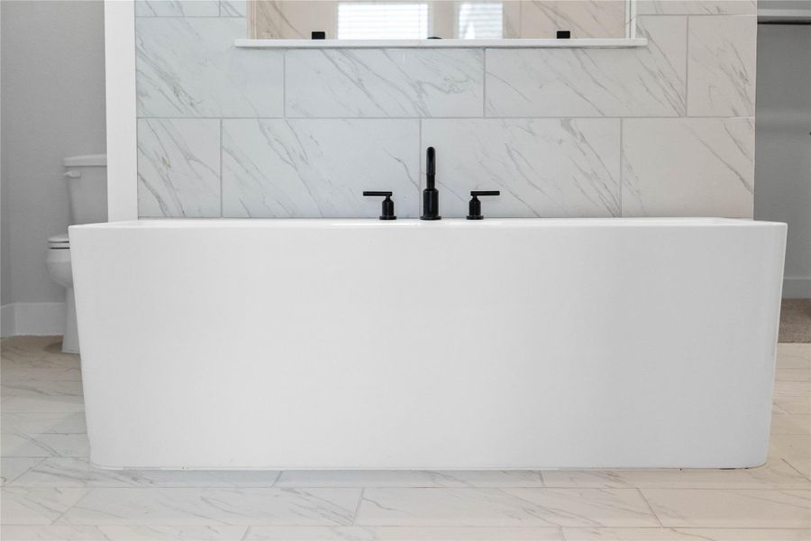 Indulge in the primary bath's deep, built-in soaking tub with elegant fixtures and a sleek tile surround for a true spa-like retreat.