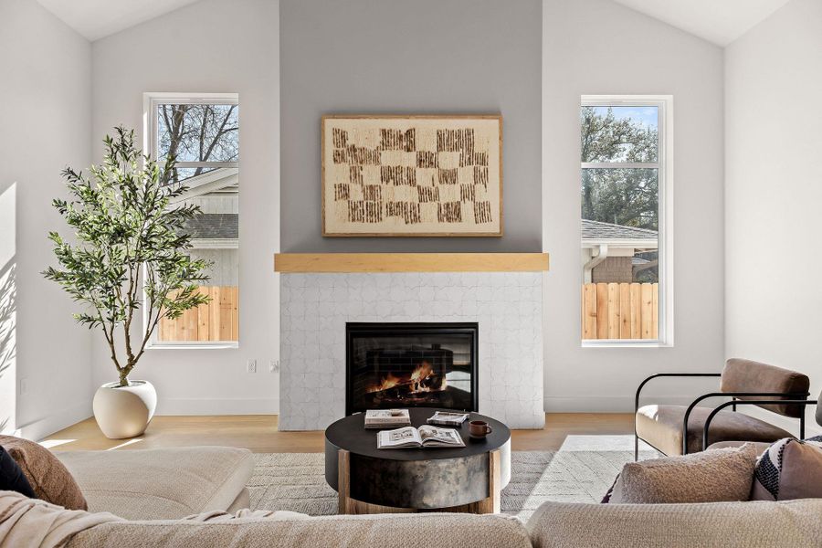 Living area with lofted ceiling, wood finished floors, and a tiled fireplace