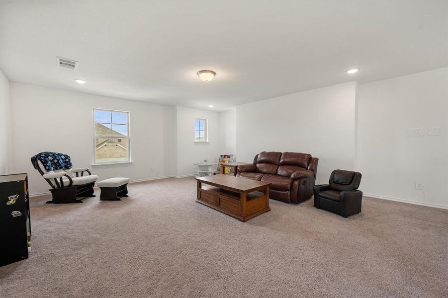 Spacious room featuring neutral carpet flooring, white walls, multiple windows, recessed lighting, and a central ceiling light fixture