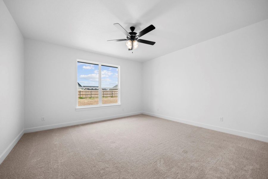 Carpeted spare room with baseboards and ceiling fan