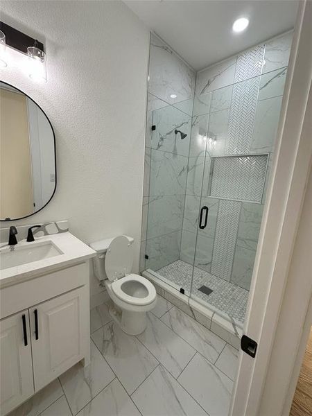 Bathroom with vanity, toilet, and an enclosed shower