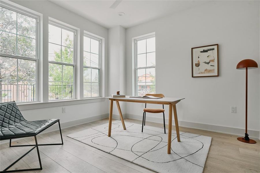 Bright room featuring light wood-finish flooring and multiple tall windows