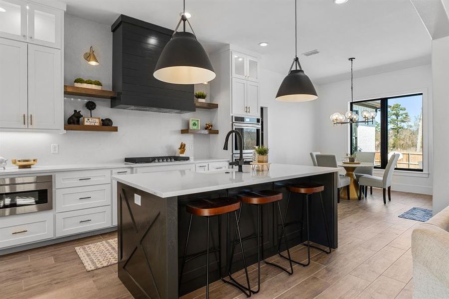 Kitchen with open shelves, light countertops, appliances with stainless steel finishes, and a sink Kitchen with open shelves, light countertops, appliances with stainless steel finishes, and a sink
