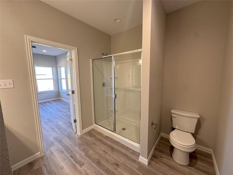 Bathroom with a shower with shower door, toilet, and wood-type flooring