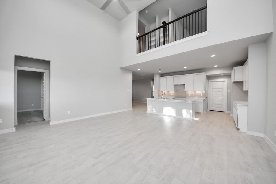 Family room flooded with natural light through the expansive windows.  The premium tile flooring adds a touch of luxury to the space, creating the perfect setting for relaxing moments and cherished gatherings with loved ones. Sample photo of completed home with similar floor plan. Actual colors and selections may vary.