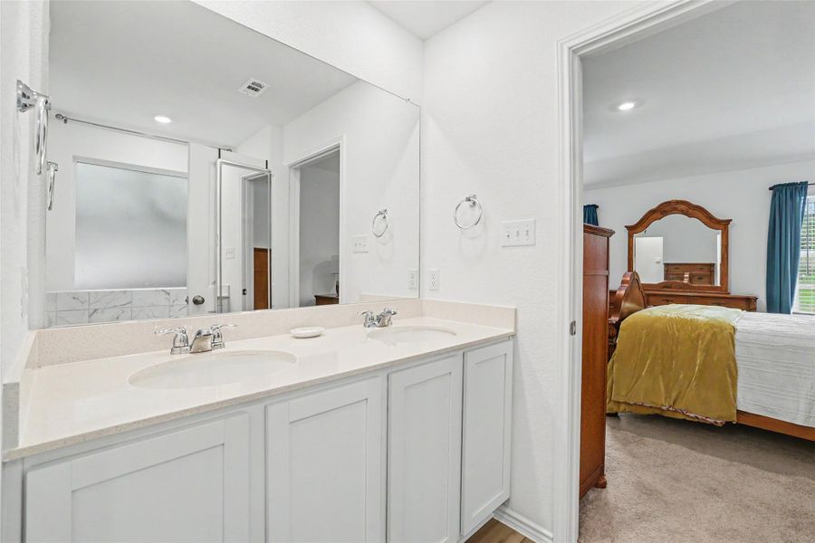 Bathroom vanity featuring dual undermount sinks, chrome faucets, and a light-toned countertop