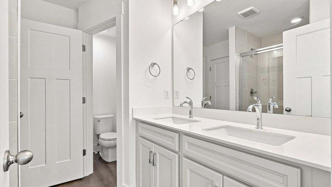 Elegant primary bathroom featuring a spacious walk-in shower and dual vanity in this first-class DRB Homes design Elegant primary bathroom featuring a spacious walk-in shower and dual vanity in this first-class DRB Homes design