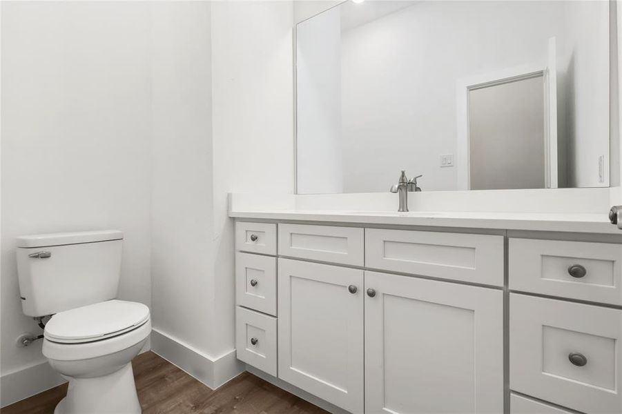 Bathroom with hardwood / wood-style floors, vanity, and toilet