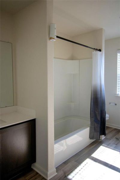 Bathroom featuring wood finished floors, shower / tub combo with curtain, and vanity